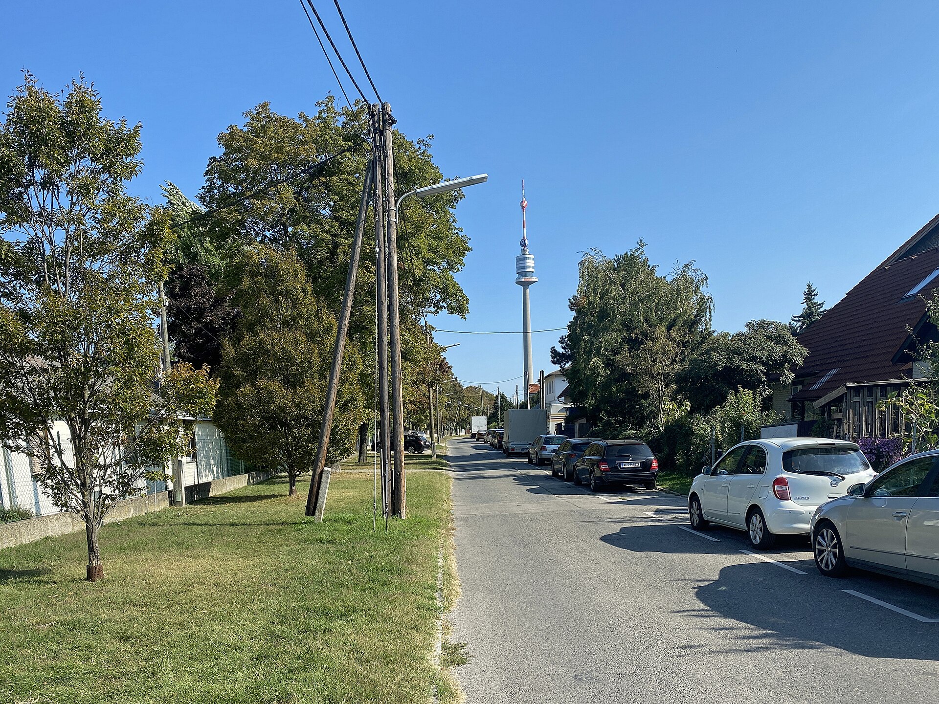 Bruckhaufner Hauptstraße mit Gärten, niedrigen Häusern und Donauturm